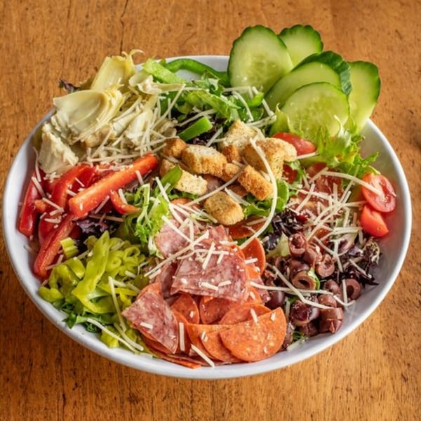 A vibrant antipasto salad with pepperoni, salami, olives, artichokes, and fresh vegetables.