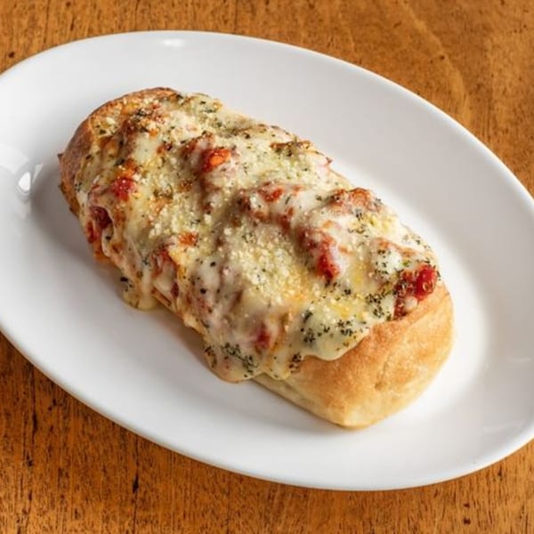 Cheesy breadstick with melted cheese, red sauce, and herbs on a white plate.